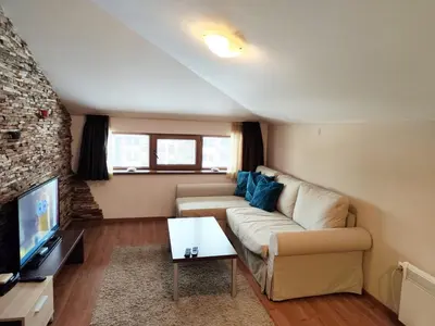a living room with a couch and a tv at Апартамент в Белведере Холидей клуб in Bansko