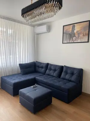 a living room with a blue couch and a chandelier at Апартамент Кashmir in Smolyan