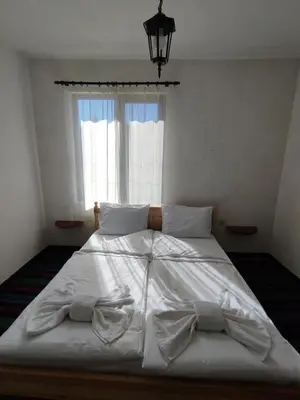 a large white bed in a bedroom with a window at Кулинарна къща за гости СОФРИЦА in Hvoyna