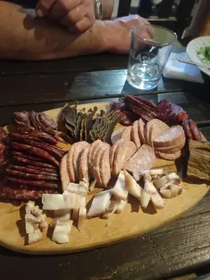 a cutting board with sausage and bacon on a table at Кулинарна къща за гости СОФРИЦА in Hvoyna