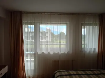 a bedroom with a window with white curtains and a bed at Mountain Paradise 1 - 2 Bedroom - Large apartment in Bansko