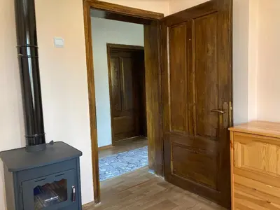 a room with a woodburning stove and a door at Диковата къща in Lesidren