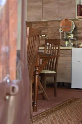 a kitchen with a wooden table and a wooden chair at Диковата къща in Lesidren