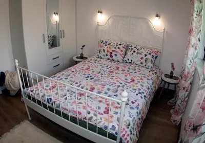 a bedroom with a white bed with a floral bedspread at Апартамент ДАРА in Smolyan