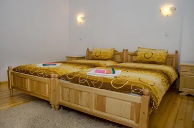 a bedroom with a wooden bed with a yellow comforter at Guest House JoJi in Sapareva Banya