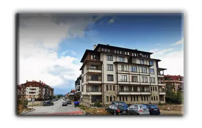 a tall building with cars parked in a parking lot at Studio Resonance Bansko in Bansko