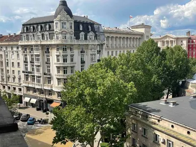 a large white building in a city with trees at Superbe last floor next Presidency in Sofia