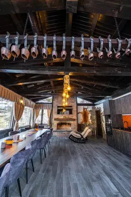 a dining room with a table and chairs and a fireplace at Планинска вила АЛТЕА in Mostowo