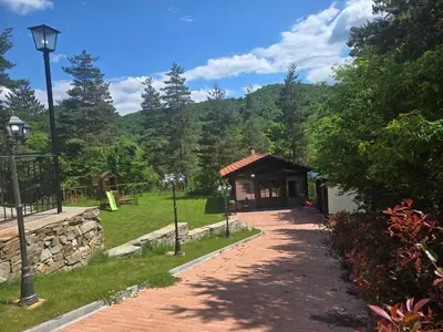 a small building in a park with a pathway at Планинска вила АЛТЕА in Mostowo