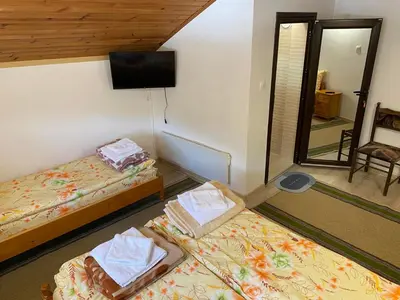 a room with two beds and a flat screen tv at Къща за гости Хриси in Mala Tsŭrkva