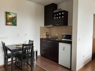a kitchen with black cabinets and a table with chairs at Spacious Studio - Bansko Royal Towers in Bansko