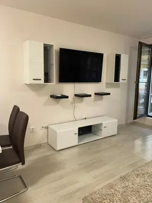 a white living room with a tv and a chair at Apartment Garden - two large terraces with hanging chairs and sunset view in Sofia