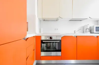 an orange and white kitchen with white cabinets at Joy Apartment - Stylish 2BD in Oborishte by Flat Mаnager in Sofia