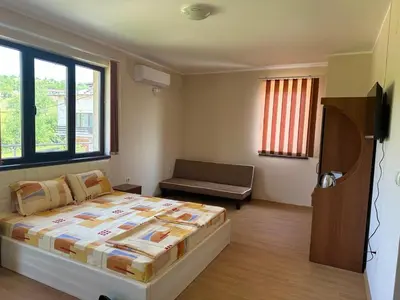 a bedroom with a large bed and a couch at Къща за гости Sunrise - Батак in Batak
