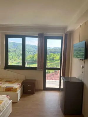 a room with two beds and a large window at Къща за гости Sunrise - Батак in Batak