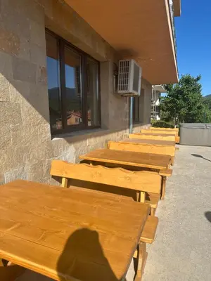 a row of wooden benches sitting outside of a building at Къща за гости Sunrise - Батак in Batak