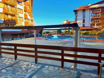 a wooden fence next to a pool with buildings at Belvedere Bansko - Cozy 1BR - Ski in Winter, Swim in Summer! by Flat Mаnаger in Bansko