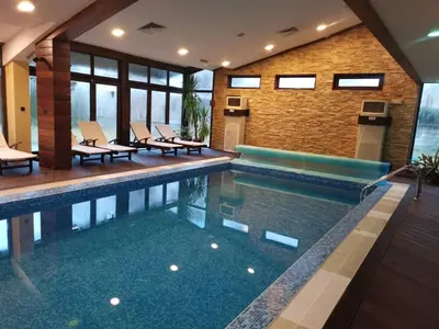 a swimming pool with chairs and a brick wall at Топ локация! in Bansko