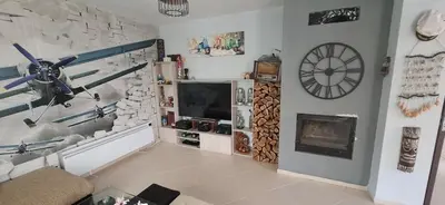 a living room with a tv and a clock on the wall at Къща за гости Спирката 2 in Hotovo