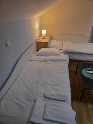 a room with two beds and a table with a lamp at Къща за гости Спирката 2 in Hotovo