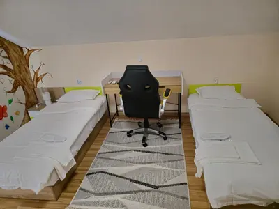a room with two beds and a desk and a chair at Къща за гости Спирката 2 in Hotovo