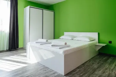 a green bedroom with a white bed with a mirror at Hrisi&Kris in Sapareva Banya