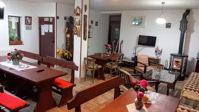 a living room with tables and chairs and a fireplace at Стаи за гости ЖиВел in Oreshak