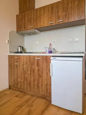 a kitchen with a white refrigerator and wooden cabinets at Orbilux - Cozy Studio in Bansko by Flat Mаnager in Bansko