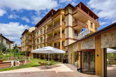 a building with an umbrella in front of it at Cozy 1BD Flat in Pirin Sense by Flat Manager in Bansko