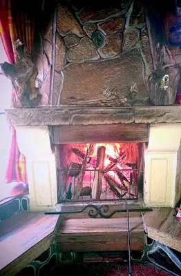 a stone fireplace with a fire in it at Villa Byala Luna - Guest House in Bistriza