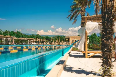 a pool at a resort with a canopy and palm trees at Mantar Spa Hotel in Marikostinovo