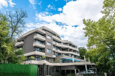 an apartment building with a parking lot and trees at SIBIYA Hotel in Ognyanovo