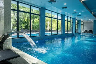 a swimming pool with a fountain in a building with windows at SIBIYA Hotel in Ognyanovo