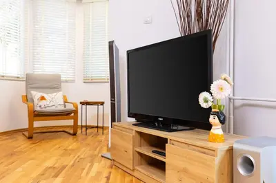a living room with a flat screen tv on a wooden entertainment center at Spacious 2BR Apt Kremena 10 minutes walk to Center in Plovdiv
