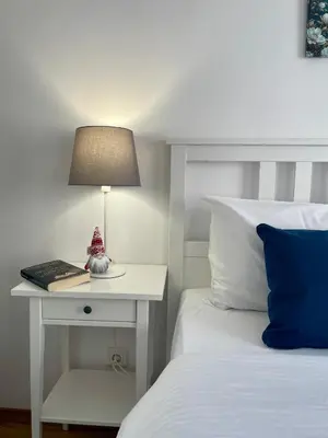 a bed with a table with a lamp and a book at Hrebet House in Borovets