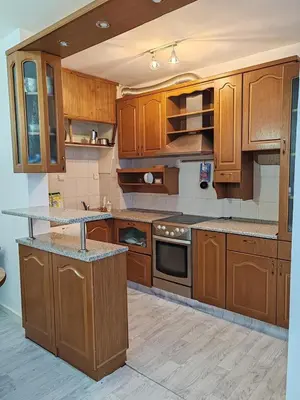 a large kitchen with wooden cabinets and counters at АПАРТАМЕНТ ДВЕ СТАИ ДО МЕТРОСТАНЦИЯ ВАРДАР Apartment In West Park near Subway in Sofia