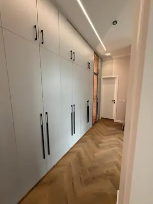 a hallway with white cabinets and a wooden floor at The Giraffe's apartment in Sofia