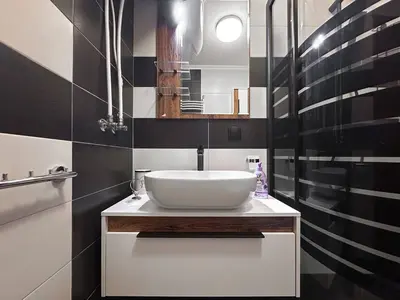 a bathroom with a white sink and black tiles at 2 Apartments, 2 Parking - Sleeps 8 - Quiet Central in Sofia