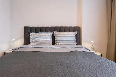 a bed with a gray comforter and two pillows at Mont Blanc Apartment in Bansko