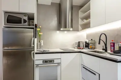 a kitchen with white cabinets and a stainless steel refrigerator at Mont Blanc Apartment in Bansko