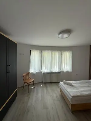 a bedroom with a bed and a chair and windows at Gorna Banya luxury apartments in Sofia