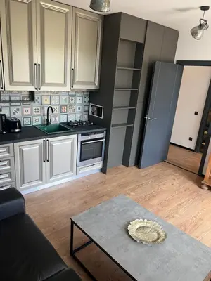 a kitchen with white cabinets and a table at Cozy apartment, by Paradise Mall in Sofia