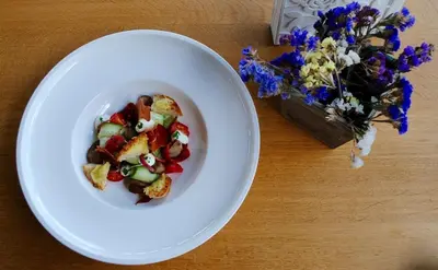 a white bowl of food next to a vase of flowers at Spacious 1BR Apartment in Central Sofia, Next to University in Sofia