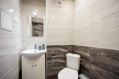 a bathroom with a white toilet and a sink at Spacious 1BDR in the Center with FREE Parking in Sofia