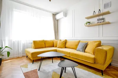 a yellow couch in a living room with a table at Stylish 2BD with Balcony & Desk near Vitosha Blvd by Flat Mаnager in Sofia