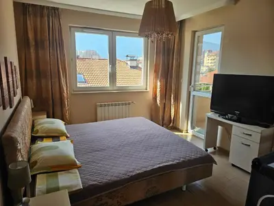 a bedroom with a bed and a tv and two windows at Bright and spacious apartment with panoramic views in Sofia