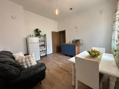 a living room with a black leather couch and a kitchen at Bright, City Centre, 1BR Apartment , Next to Sofia University in Sofia
