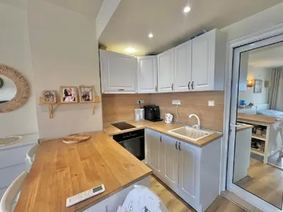 a kitchen with white cabinets and a wooden counter top at Слънчево Студио Алпин Банско! in Bansko