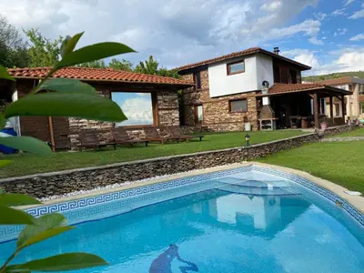 a villa with a swimming pool in front of a house at Къщата на тати in Garmen