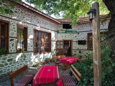a building with red tables and benches in front of it at Стария Чинар in Melnik
